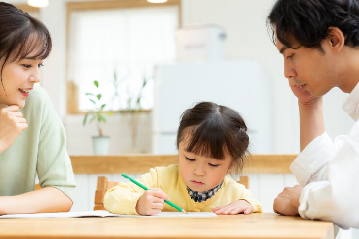 両親と一緒に勉強する2歳の女の子